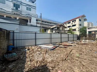 Vacant land plot in urban area ready for development, surrounded by buildings and clear blue sky.