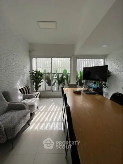 Modern study room with large table, stylish chairs, and natural light from large windows.