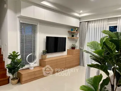 Modern living room with sleek TV unit, indoor plants, and elegant decor.