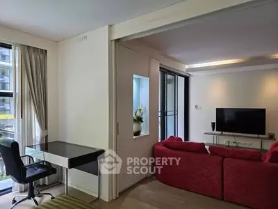 Spacious living room with red sofa, TV, and study area in modern apartment