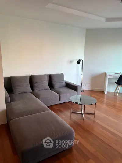 Modern living room with sleek grey sofa and wooden flooring
