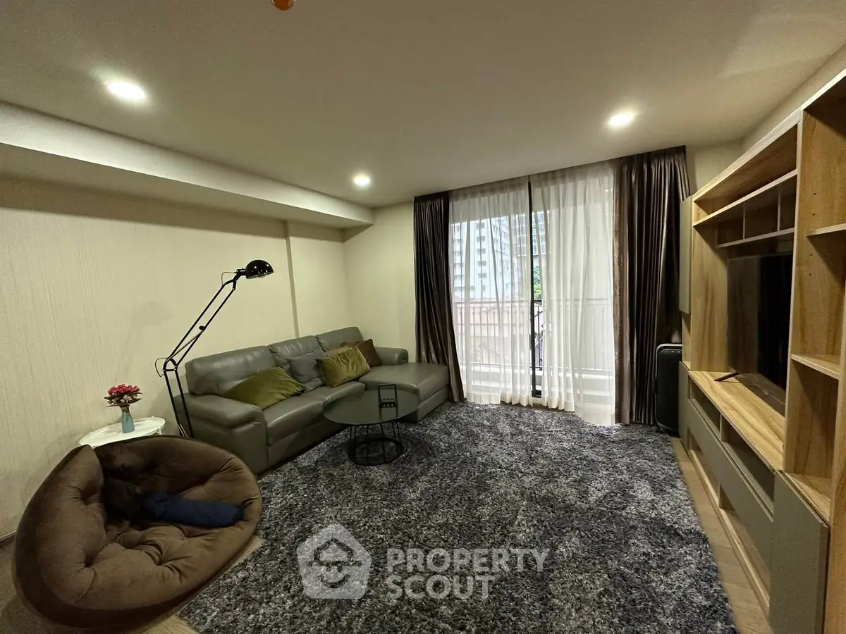 Spacious living room with modern decor and large window offering natural light.