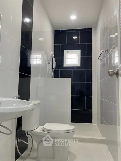 Modern bathroom with sleek black and white tiles and contemporary fixtures.