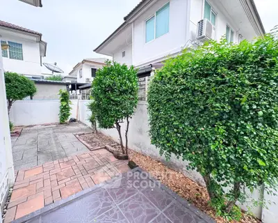 Charming suburban garden with paved walkway and lush greenery, perfect for outdoor relaxation.