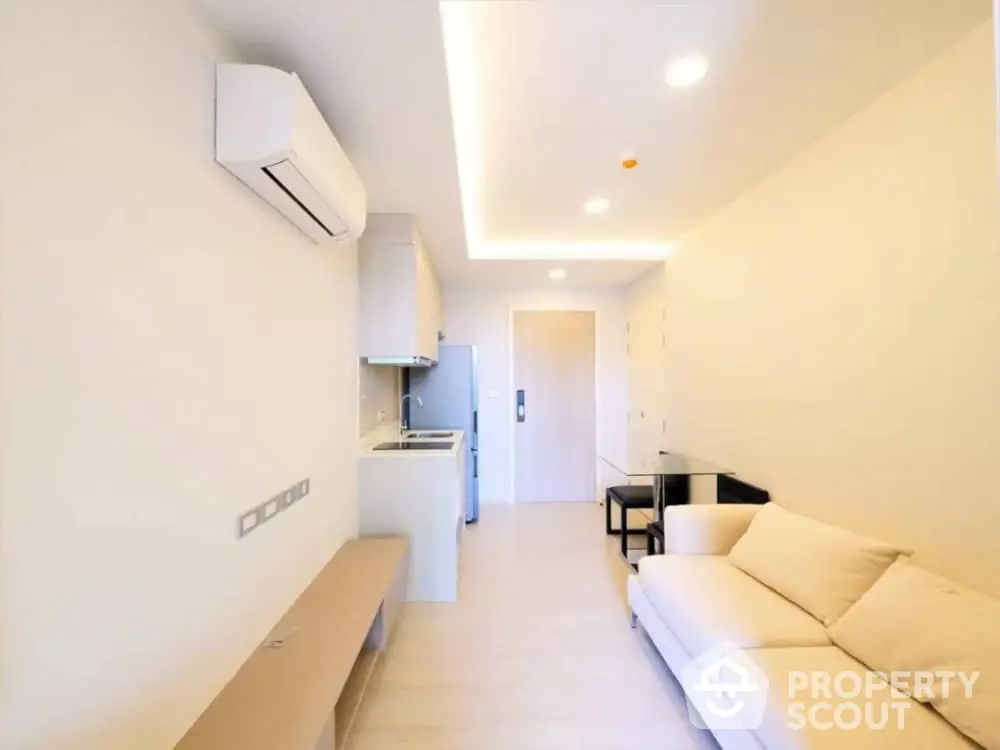 Bright and modern studio apartment with sleek finishes, featuring an open layout kitchen, comfortable living space, and ample lighting.