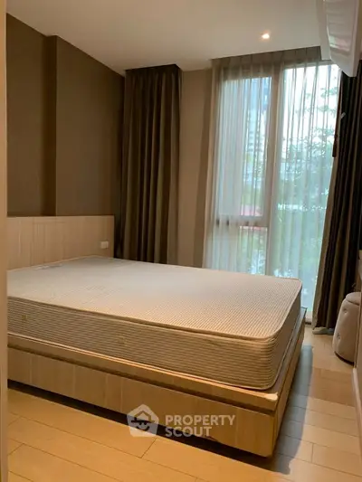 Cozy bedroom with large window and modern furnishings in a stylish apartment.