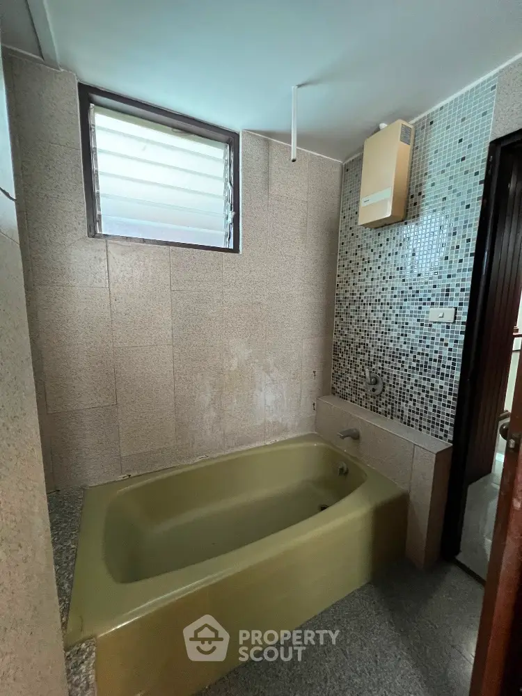 Cozy bathroom with vintage bathtub and mosaic tile wall accent