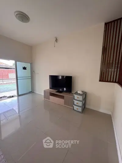 Spacious living room with modern TV setup and large windows for natural light.