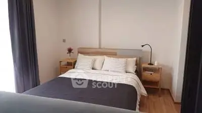 Cozy bedroom with modern decor and natural light, perfect for relaxation.