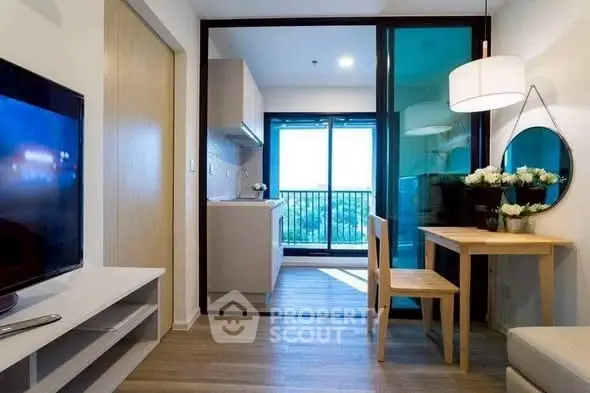 Modern living room with open kitchen and balcony view, featuring sleek furniture and bright lighting.