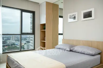 Modern bedroom with city view, featuring sleek design and large window for natural light.