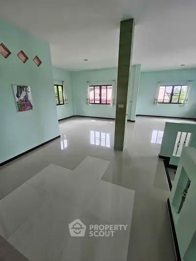 Spacious open-plan living area with large windows and glossy tiled floors, perfect for modern living.