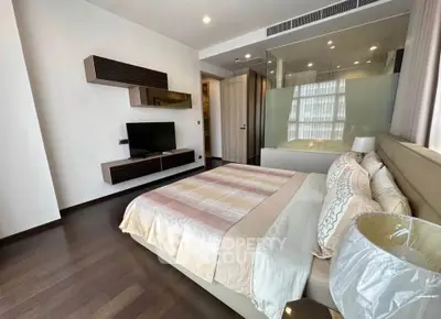 Luxurious bedroom with modern decor and glass partition overlooking a sleek bathroom.