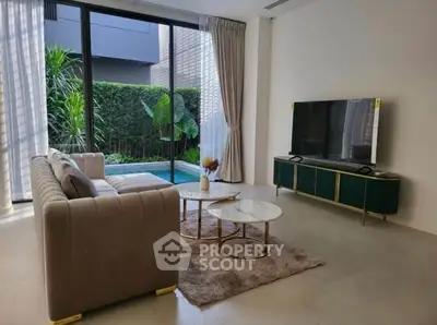 Modern living room with pool view, elegant sofa, and sleek TV setup.