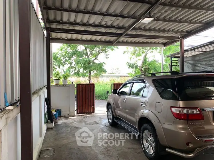 Spacious covered parking area with SUV and garden view.