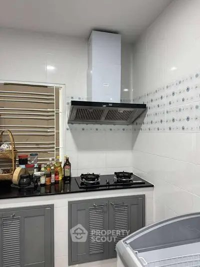 Modern kitchen with sleek cabinets and gas stove, featuring stylish backsplash and ample counter space.
