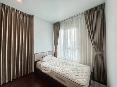 Cozy bedroom with large window and elegant curtains, perfect for relaxation and comfort.