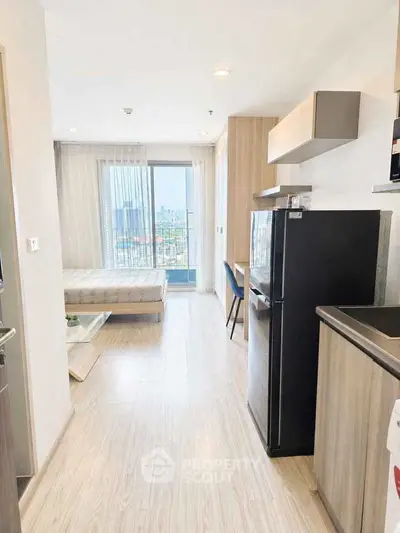 Modern studio apartment with open layout and city view, featuring sleek kitchen and cozy living area.