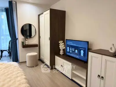 Modern bedroom with stylish furniture and TV, featuring elegant decor and natural light.