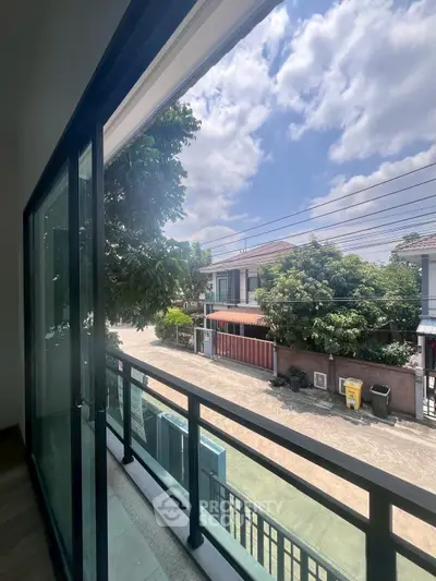 Spacious balcony with sliding glass doors offering a serene neighborhood view under a clear blue sky.