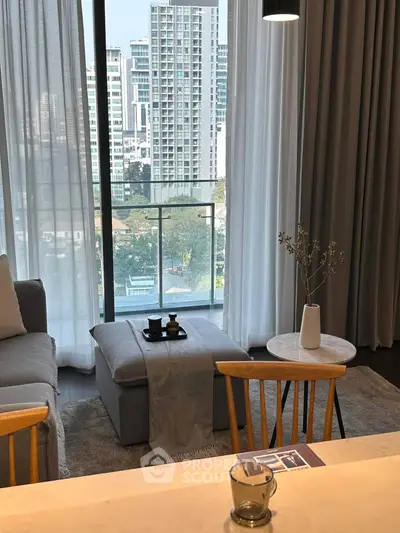 Modern living room with city view, featuring elegant decor and floor-to-ceiling windows.