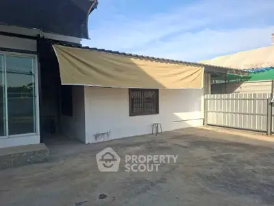 Charming exterior view of a cozy home with a spacious concrete yard and awning.
