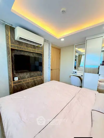Luxurious bedroom with modern decor, featuring a wall-mounted TV and elegant lighting.