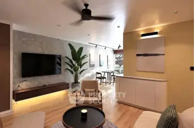 Modern living room with stylish decor and open layout, featuring a large TV and elegant lighting.