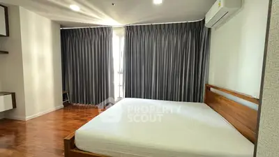 Spacious bedroom with wooden flooring and modern furnishings