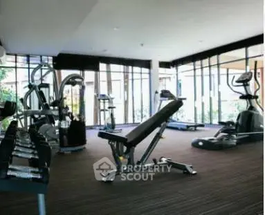 Spacious gym with modern equipment and large windows in luxury real estate property.