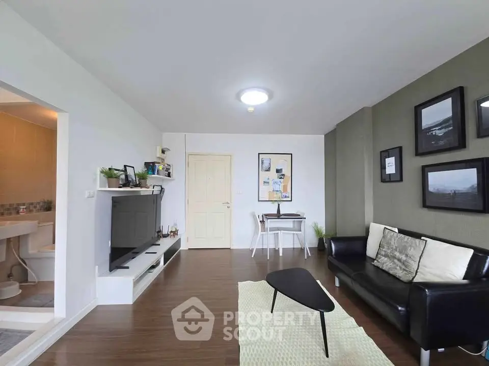 Modern living room with sleek furniture and wall art, adjacent to a cozy dining area.