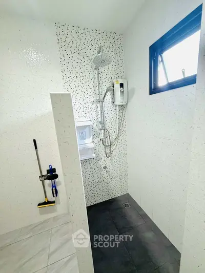 Modern bathroom with shower and window, featuring sleek tiles and practical design.