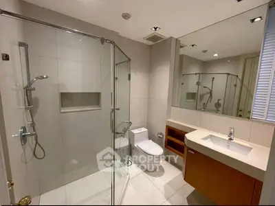 Modern bathroom with glass shower and sleek fixtures in upscale apartment.