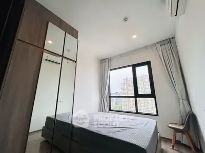 Modern bedroom with large window and city view, featuring sleek wardrobe and air conditioning.