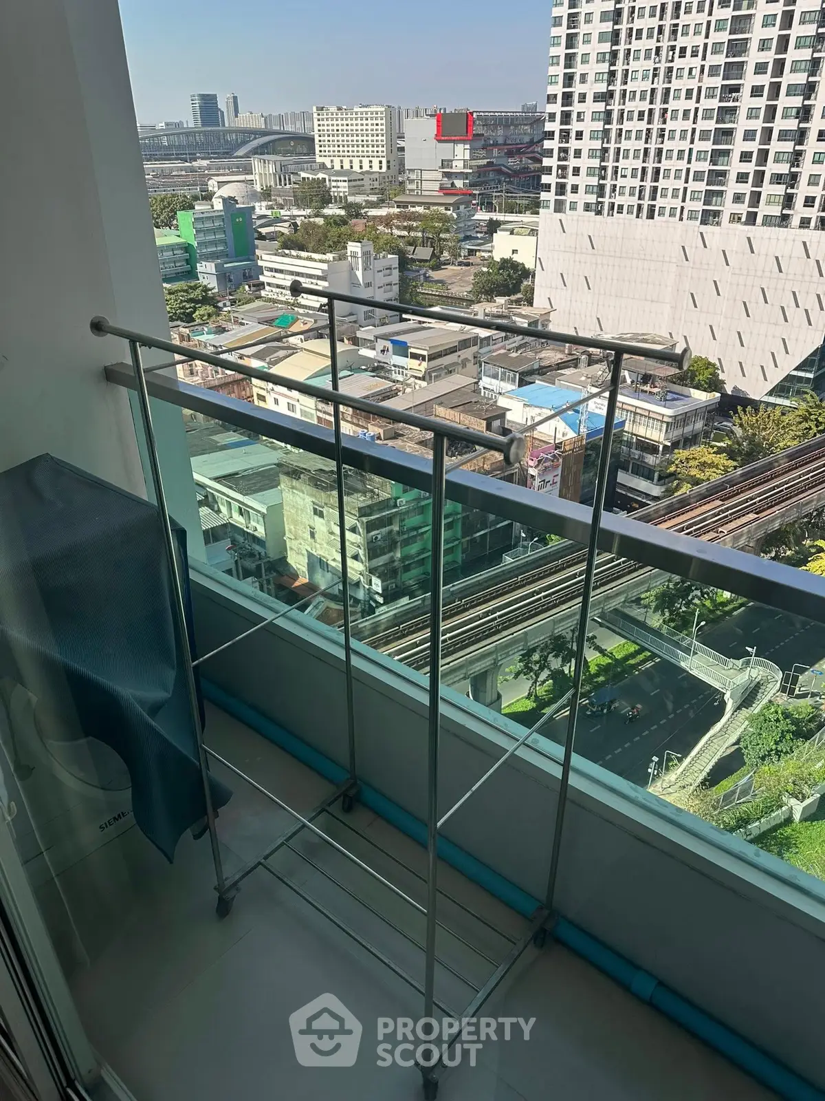 High-rise balcony with cityscape view and drying rack, perfect for urban living.