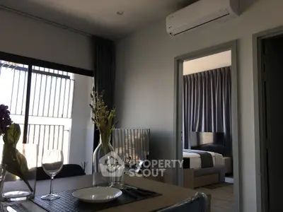 Modern apartment interior with dining area and bedroom view, featuring sleek furniture and natural light.