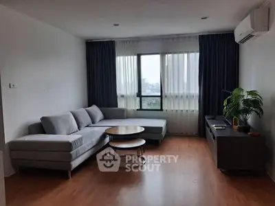 Spacious living room with modern gray sectional sofa and large window view.