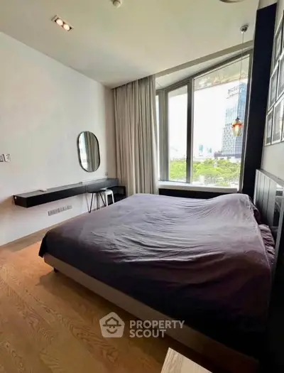 Modern bedroom with large window and city view, featuring a sleek design and natural light.
