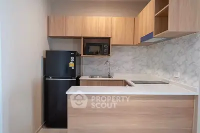 Modern kitchen with sleek cabinets, marble backsplash, and black fridge in a compact layout.