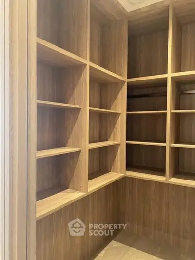 Spacious walk-in closet with wooden shelving and ample storage space.