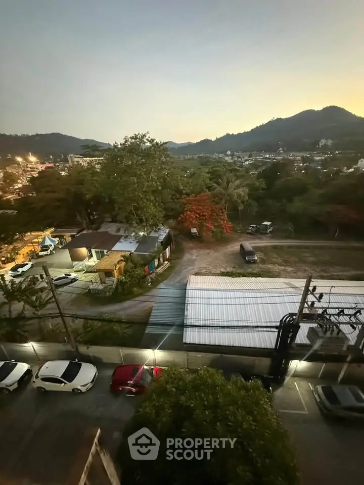 Scenic view from a high-rise apartment overlooking lush greenery and distant hills at dusk.