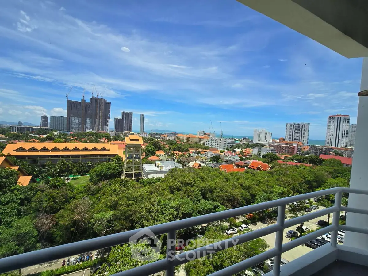 Stunning cityscape view from a high-rise balcony overlooking lush greenery and urban skyline.