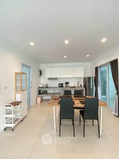 Modern kitchen with sleek white cabinets and dining area in open layout design.