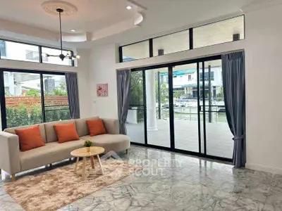 Spacious living room with large windows and garden view, featuring modern decor and natural light.