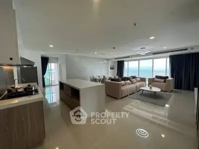 Spacious open-plan living room with ocean view and modern kitchen.