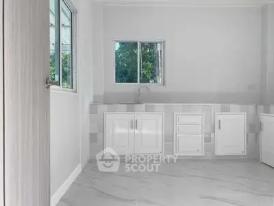 Modern kitchen with white cabinets and large windows offering natural light.