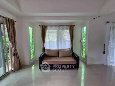 Spacious living room with large windows and elegant curtains, perfect for natural light and relaxation.