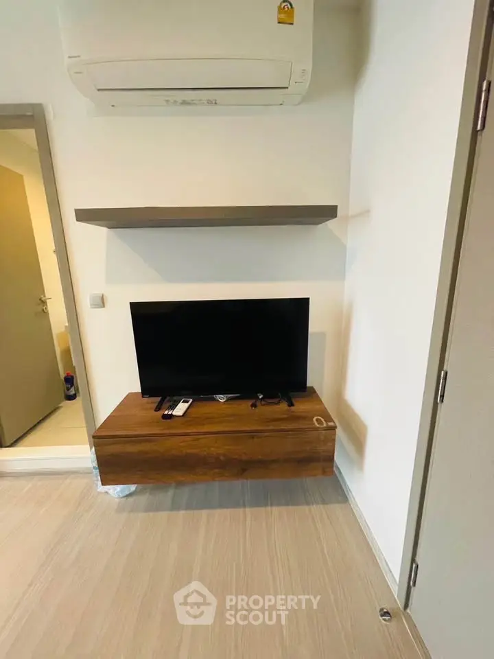 Modern living room corner with TV, floating shelf, and air conditioning unit.