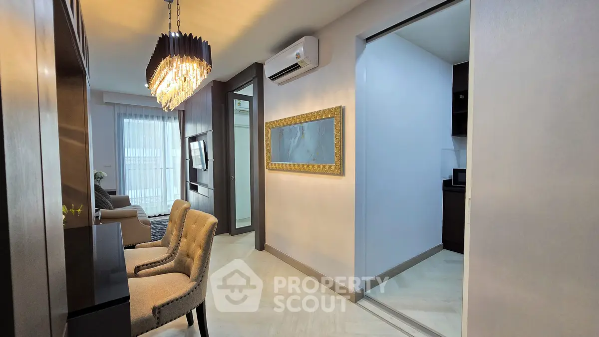 Modern living room with elegant chandelier and cozy seating area in a stylish apartment.