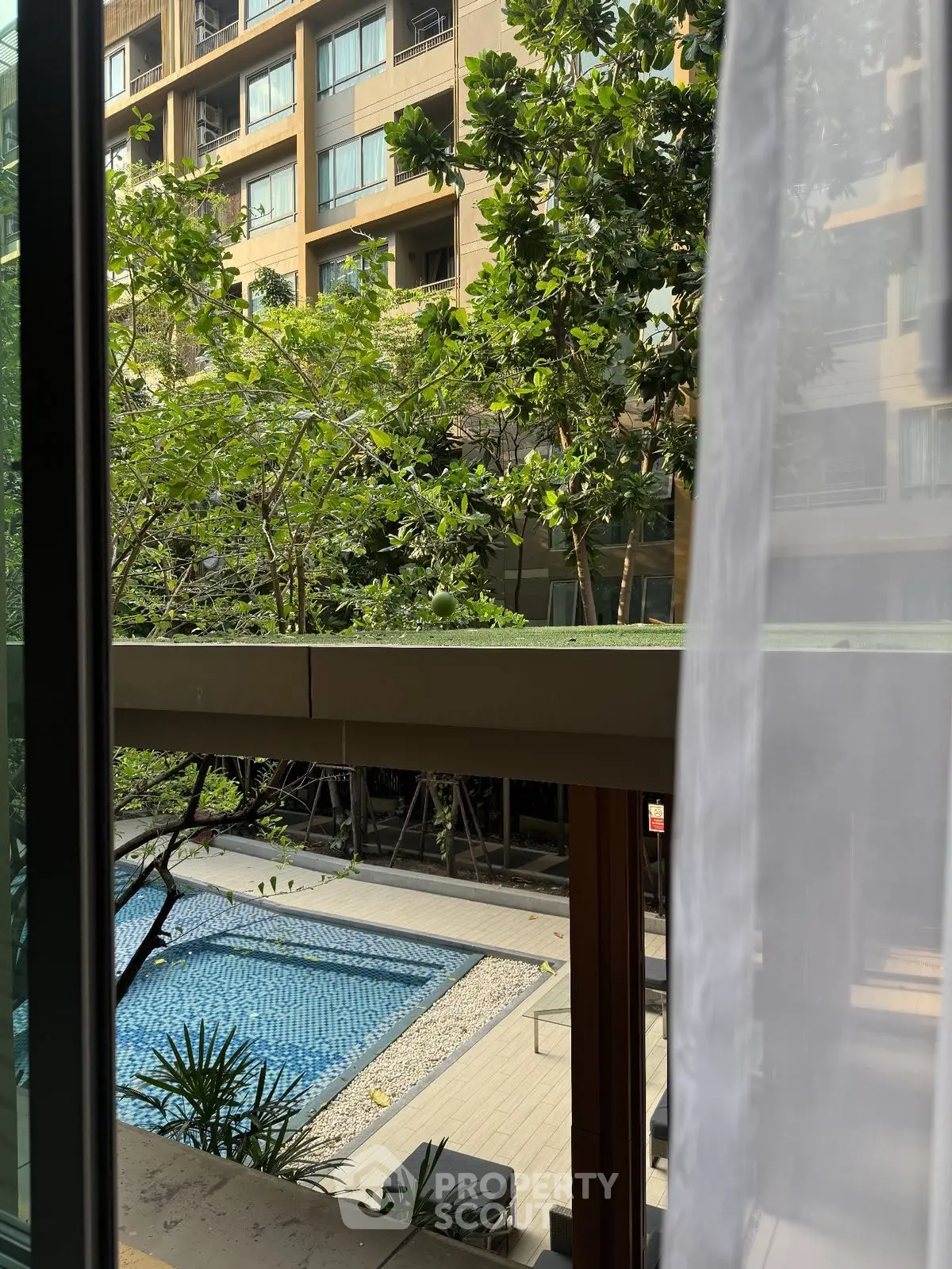 Luxurious apartment view overlooking a serene pool and lush greenery